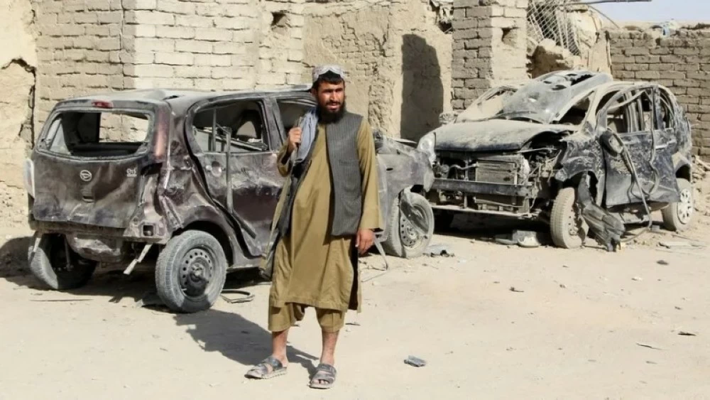 مقاتل من طالبان بجوار سيارات مدمرة جراء غارة باكستانية.