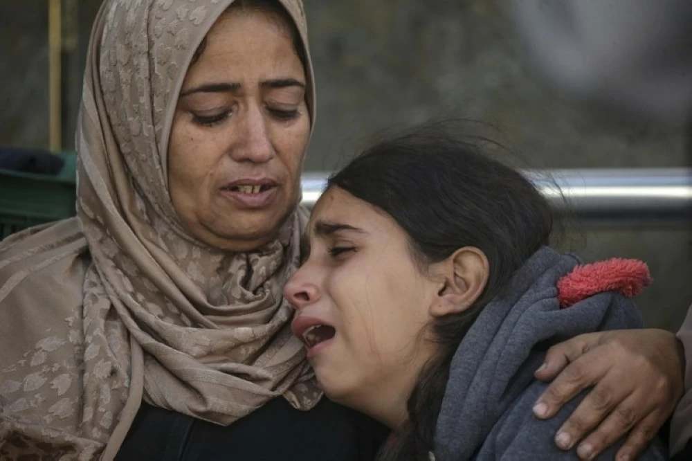  فلسطينيتان تبكيان مقتل أقاربهن في غارات إسرائيلية على غزة.(إ ب أ)