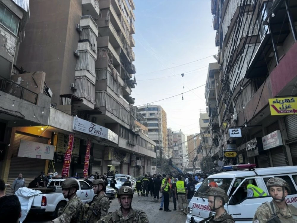 يقف جنود وعناصر الإنقاذ في موقع الغارة الجوية الإسرائيلية التي استهدفت الضاحية الجنوبية في بيروت اليوم. (إ ب أ)