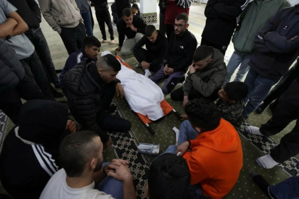 فلسطينيون بجوار جثمان شاب قتلته قوات الاحتلال في قرية قباطية جنوب جنين بالضفة الغربية.( إ ب أ)