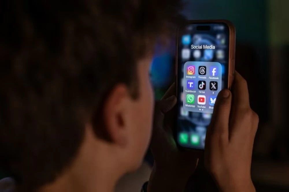 صورة تعبيرية لطفل يحدّق بشاشة الهاتف المحمول