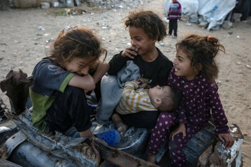 أطفال نازحون يلعبون بالقرب من مخيم مؤقت في خان يونس، جنوب قطاع غزة (إ ب أ)