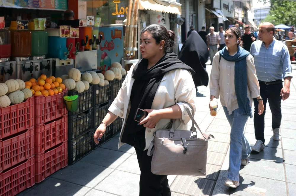 إيرانيون يسيرون في أحد شوارع طهران (إ.ب.أ).