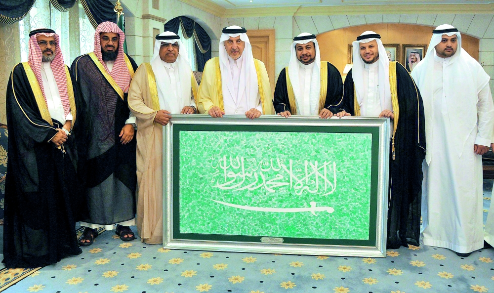 الأمير خالد الفيصل متسلما لوحة الخفاق الأخضر التي بصم عليها 10 آلاف طالب وطالبة. (واس)
