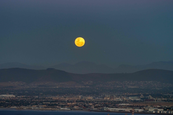 TOPSHOT -  The 'Super' full moon rises above the Table Bay harbour, and the central city, on November 14, 2016, in Cape Town.  This 'Extra Supermoon'  appears 14% bigger and 30% brighter than usual and this is the closest it's come to earth since 1948. The moon is 14% closer to earth than its farthest point or apogee, and will not come this close to earth again, until 34 years from now. / AFP / RODGER BOSCH
