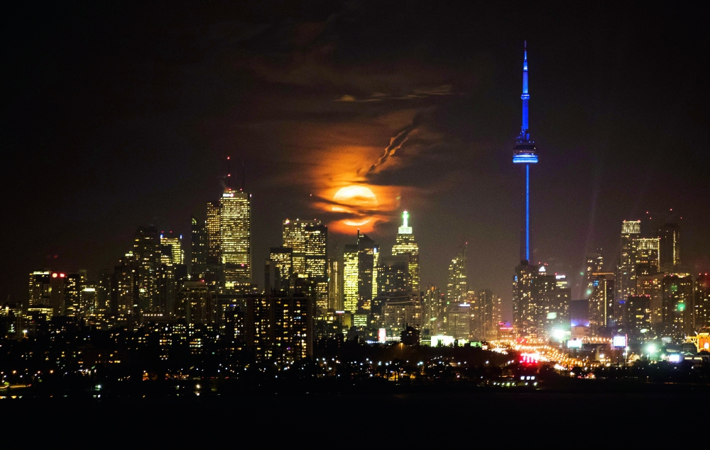 The full moon rises over the Toronto skyline Monday, Nov. 14, 2016. The phenomenon known as the supermoon occurs because the moon follows an elliptical orbit around the Earth. This week, the moon is coming closer to the Earth than at any time since January 1948. (Mark Blinch/The Canadian Press via AP)