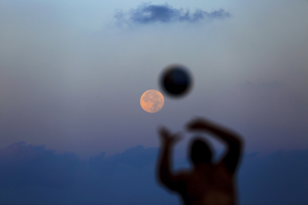 The moon sets behind a Lebanese man playing beach volleyball with his friends on the seafront promenade in Beirut, Lebanon, Tuesday, Nov. 15, 2016. The brightest moon in almost 69 years lit up the sky, during its closest approach to earth as the 