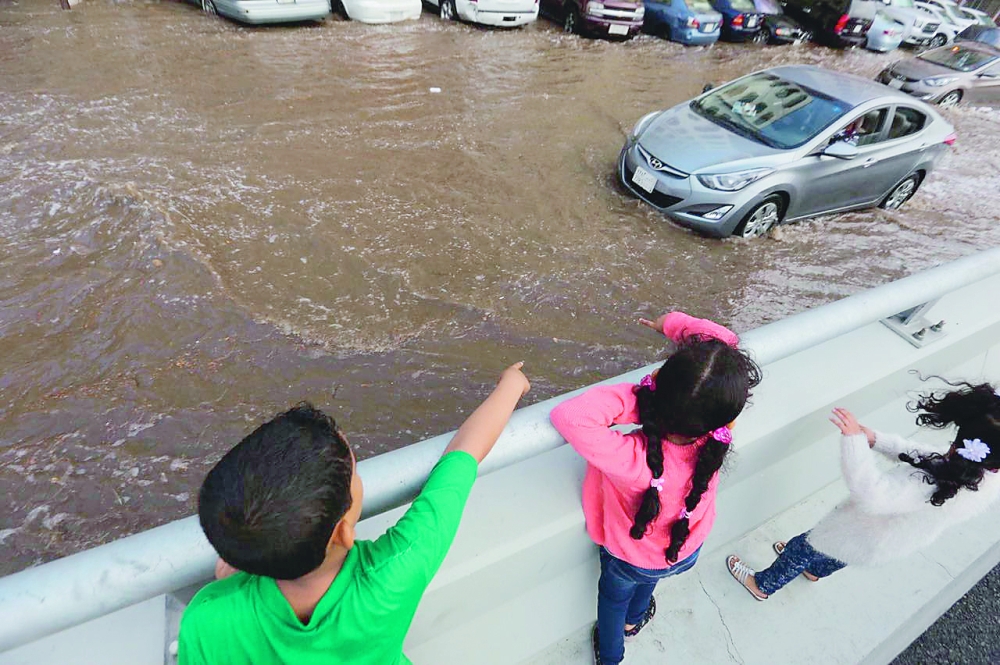 أطفال يشاهدون تجمعاً لمياه الأمطار. (تصوير: مديني عسيري)