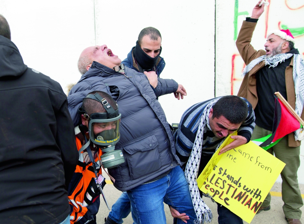 إجلاء مصور وكالة «أسوشيتد برس» لإصابته بقنبلة مسيلة للدموع في صدام لمتظاهرين فلسطينيين مع قوات الاحتلال في بيت لحم أمس. (أ. ب)