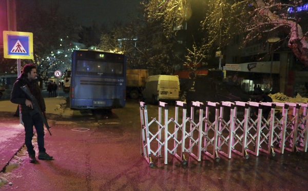 A Turkish police officer stands at the entrance of popular Tunali Hilmi Street, closed with trucks and buses against possible car bomb attacks, in Ankara, Turkey, early Sunday, Jan. 1, 2017. An assailant believed to have been dressed in a Santa Claus costume and armed with a long-barrelled weapon, opened fire at a nightclub in Istanbul's Ortakoy district during New Year's celebrations, killing dozens of people and wounding dozens of others in what the province's governor described as a terror attack.(AP Photo/Burhan Ozbilici)