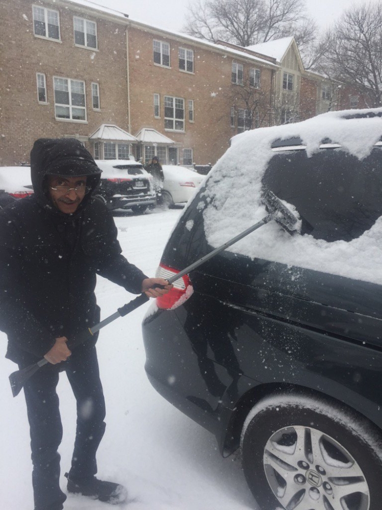 حمود أبو طالب يزيح الثلج عن نوافذ سيارته.