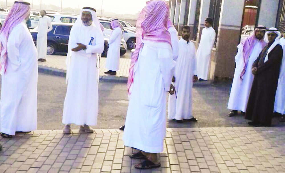موظفو الشركة المشغلة أمام باب فرع مكتب العمل بالمدينة المنورة أمس. (تصوير: عبدالمجيد الدويني)