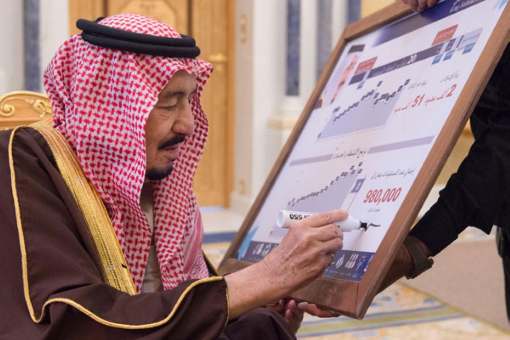 خادم الحرمين يوقع على لوحة تحكي مسيرة مركز الملك سلمان الاجتماعي خلال استقباله أعضاء مجلس إدارة المركز أمس في الرياض (واس)