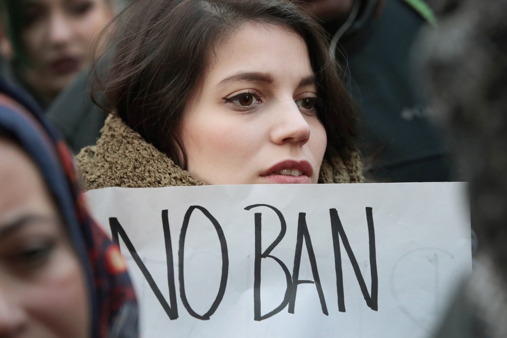 متظاهرة أمريكية تحمل شعار «لا لحظر دخول المسلمين» أمام مطار أوهيير في شيكاغو أمس. (أ. ف. ب)