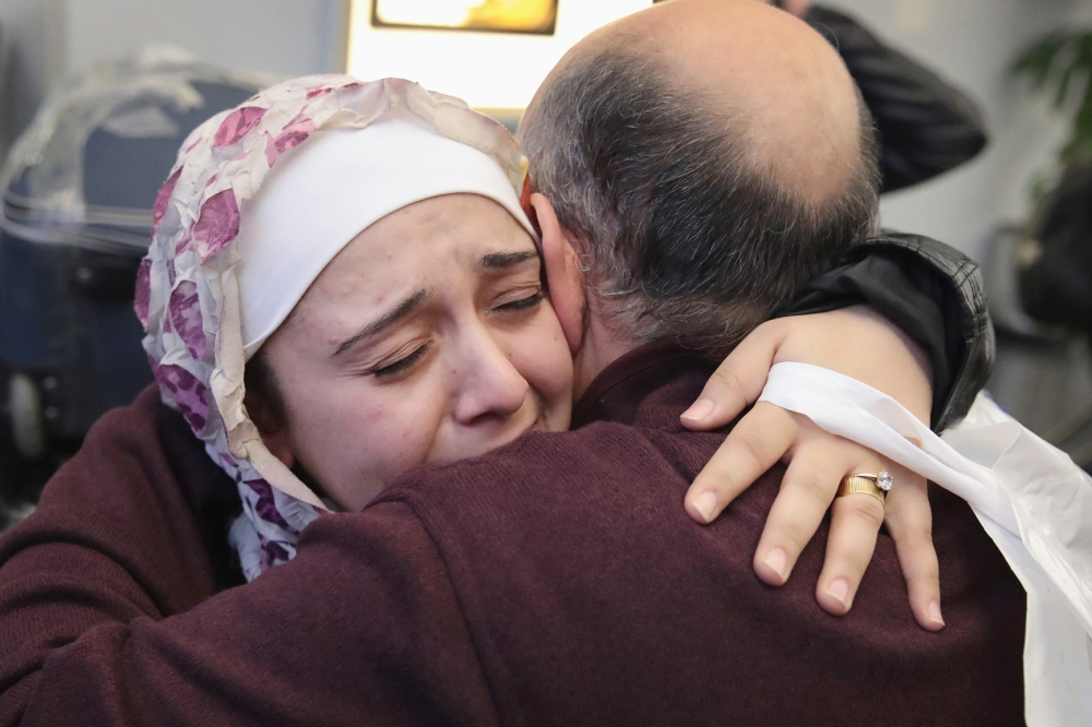 سوري يحتضن ابنته التي وصلت إلى مطار شيكاغو بعد تعليق العمل بقرار الحظر. (أ. ف. ب)