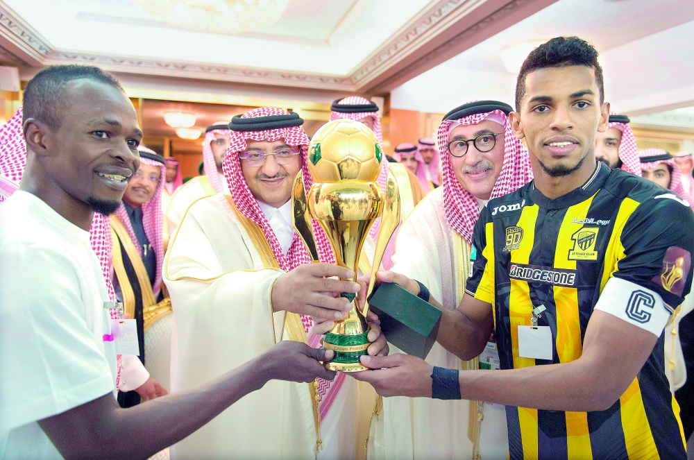 



نائب الملك، الأمير محمد بن نايف، متوجا قائد الاتحاد أحمد عسيري بكأس البطولة، ويبدو زميله عدنان فلاته.   (واس)