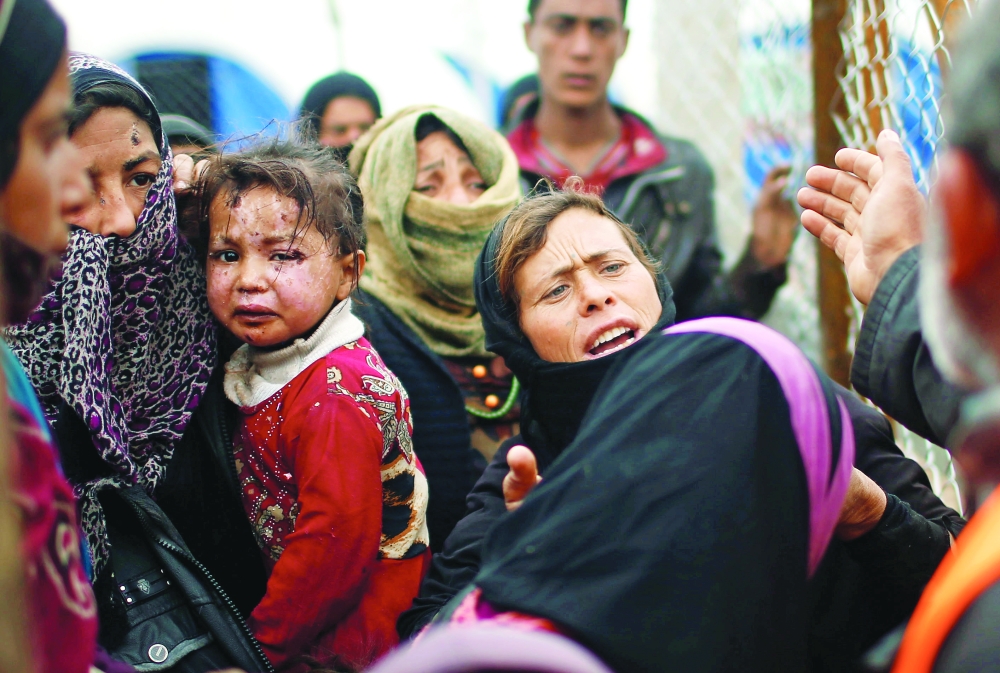 عراقية تحمل طفلتها وتبدو عليهما آثار جروح جراء  المعارك الدامية في الموصل. (رويترز)