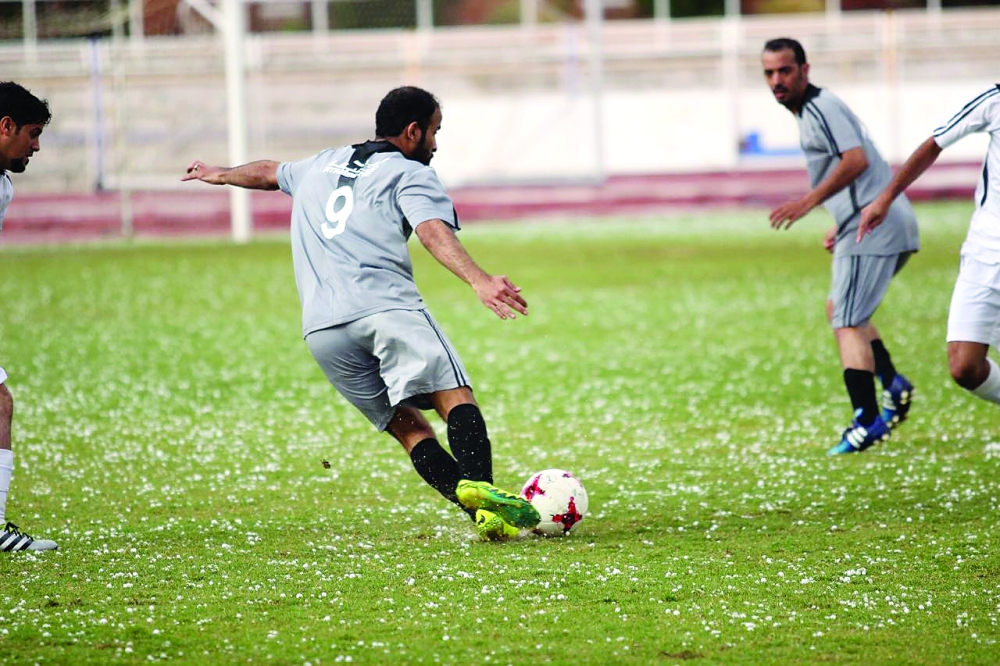 اللاعبون قبل توقف المباراة، ويبدو البرد على أرضية الملعب. (عكاظ)