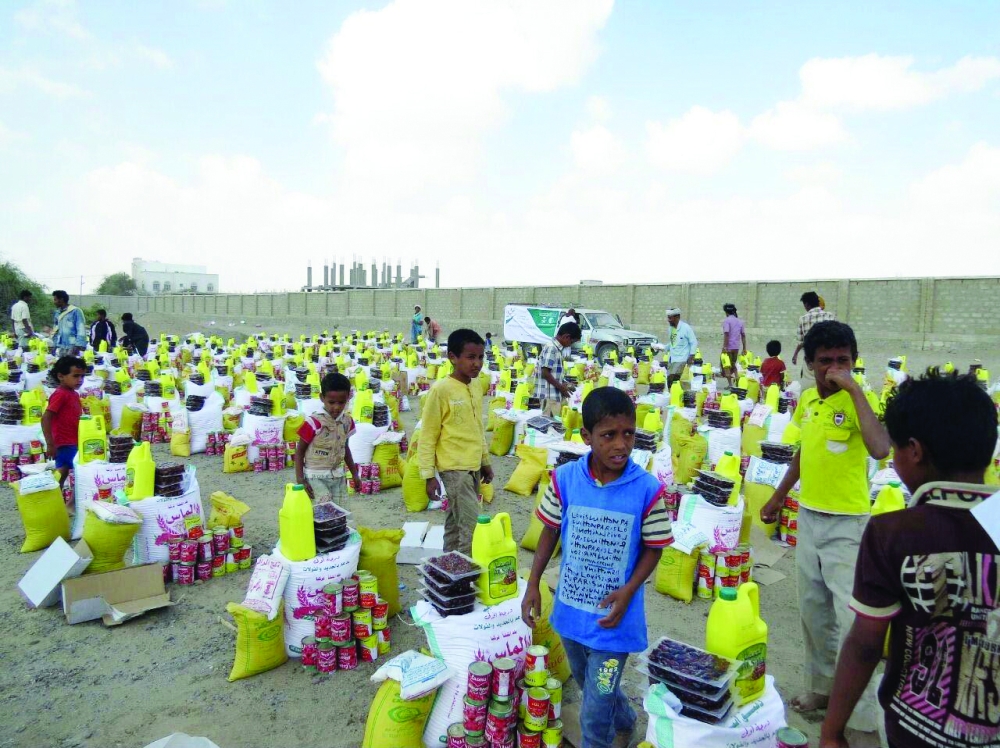 أطفال يمنيون يستلمون مساعدات غذائية من إحدى الحملات الإغاثية السعودية. (عكاظ)