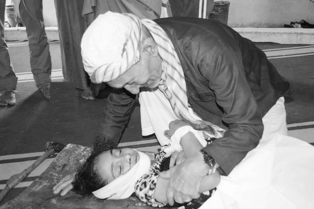 يمني يلقي نظرة الوداع على ابنته التي قتلتها ميليشيا الانقلاب في تعز أمس. (متداولة)