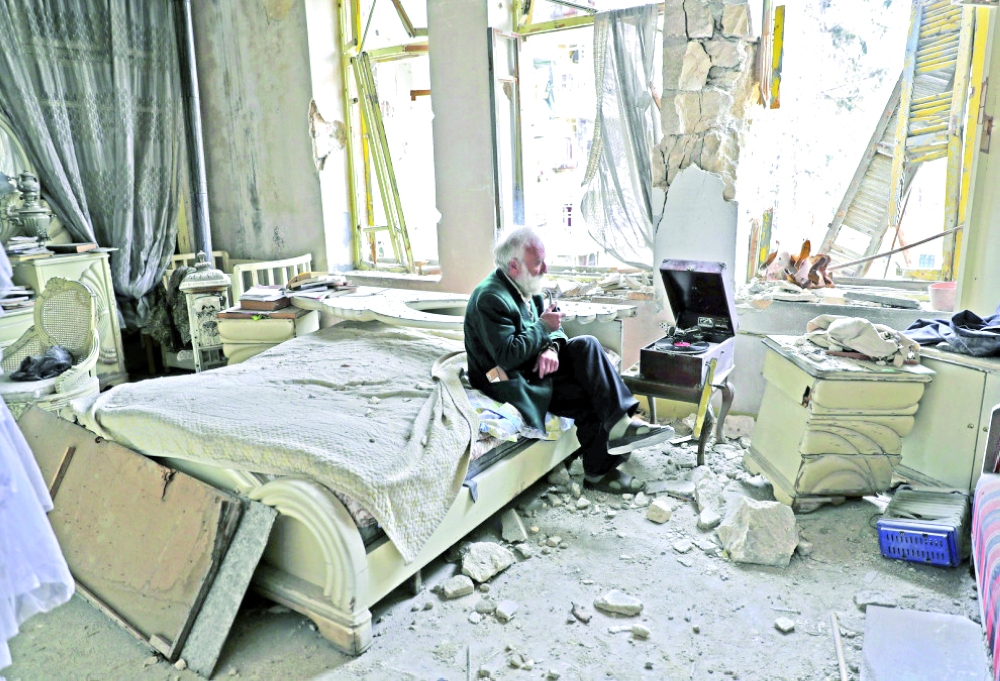 مسن ينصت إلى الموسيقى في منزله المتهدم في مدينة حلب أخيراً.  (أ. ف. ب)