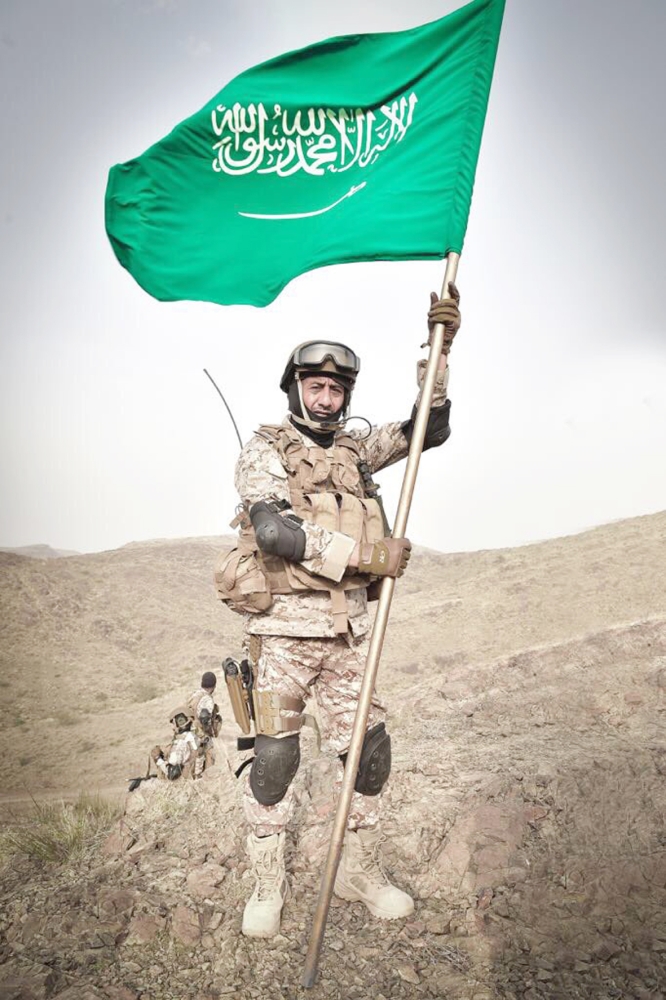 ناصر القصبي يحمل العلم السعودي خلال زيارته أخيراً للحد الجنوبي.  (عكاظ)