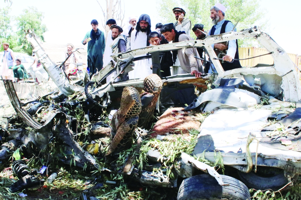 أفغان يعاينون سيارة تضررت جراء هجوم انتحاري في محافظة خوست أمس. (رويترز)
