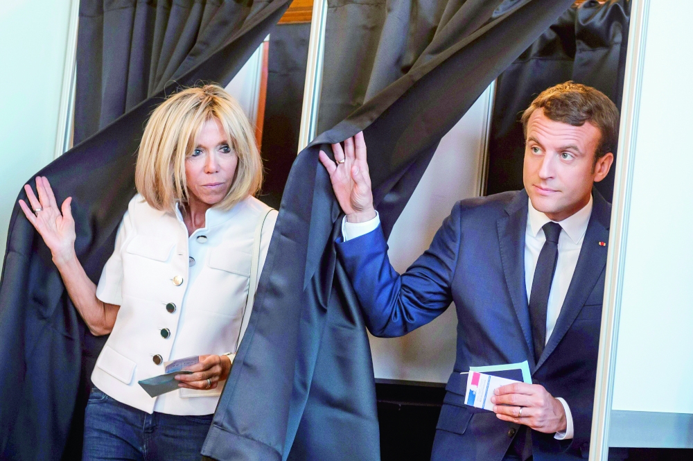 



 ماكرون وزوجته بريجيت يدليان بصوتيهما في الانتخابات التشريعية الفرنسية أمس. (أ ف ب)