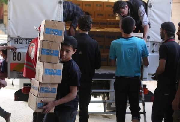 Syrians unload boxes of aid donated by UNHCR in the rebel held and besieged town of Harasta, in the Eastern Ghouta region outside Damascus, on Jun 19, 2017. The United Nations estimates more than 600,000 people in Syria are living under siege, a tactic employed primarily by government forces, but also used by rebel fighters and the Islamic State group. / AFP / AMER ALMOHIBANY
