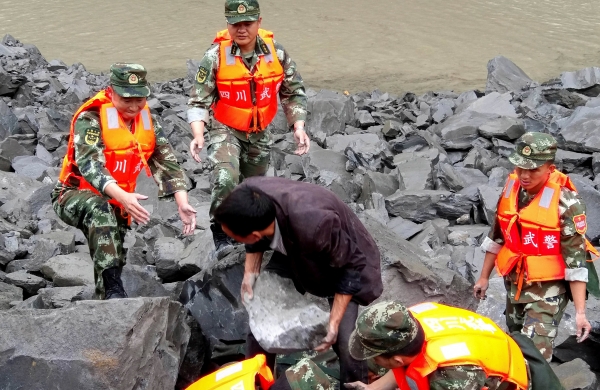  موظفو الإنقاذ في موقع انهيار أرضي دمر نحو 40 أسرة في قرية شينمو أمس. ( رويترز). 