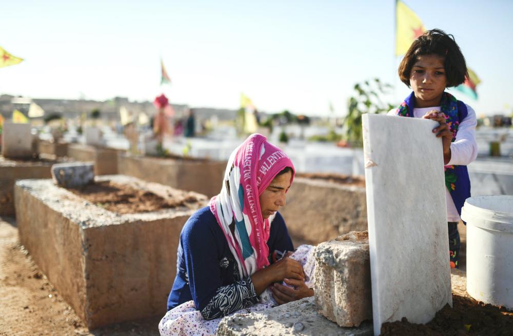 A woman whose husband was killed in the US-backed Kurdish and Arab forces' battle of Raqa, the main Syrian stronghold of the Islamic State group, visits a cemetary in the Kurdish town of Kobane in northern Syria, on July 16, 2017.
More than 330,000 people have been killed in the Syrian conflict since it started six years ago, around a third of them civilians, a monitor said. The Britain-based Syrian Observatory for Human Rights said it has documented the deaths of 331,765 people across Syria since the conflict erupted in mid-March 2011 with anti-government protests.
/ AFP / BULENT KILIC 