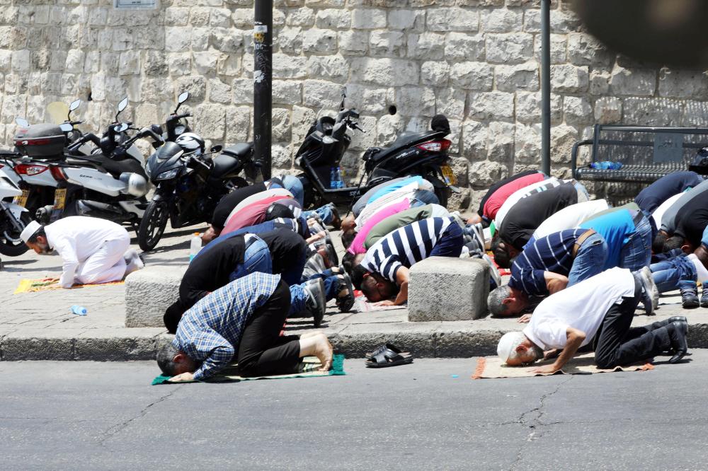 



فلسطينيون يصلون خارج البلدة القديمة في القدس احتجاجا على الإجراءات الإسرائيلية. (رويترز)