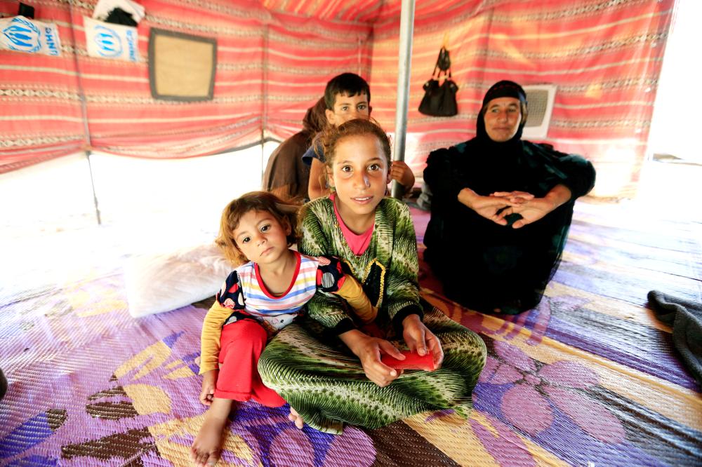 عراقية نازحة من الموصل تجلس مع أطفالها في خيمة بمعسكر للنازحين.  (رويترز)