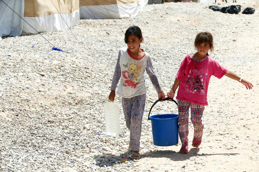 طفلتان تنقلان الماء في المعسكر ذاته، أمس الأول. (رويترز)