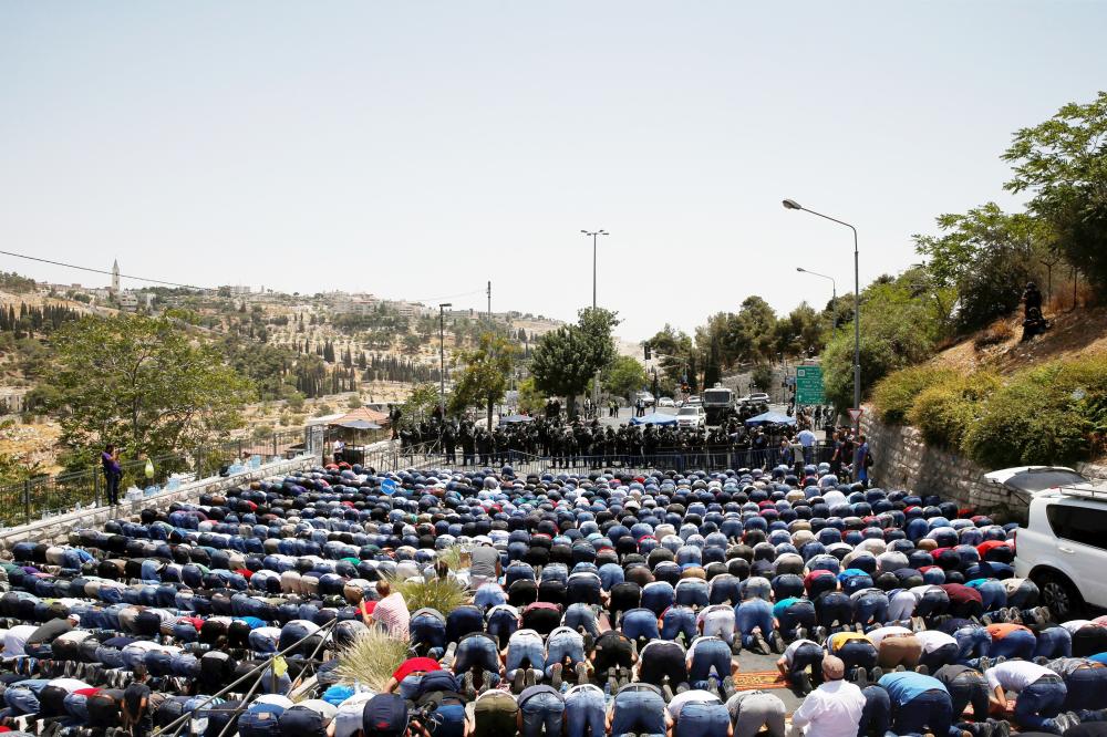 



فلسطينيون يصلون الجمعة في شارع خارج القدس القديمة أمس. (رويترز)