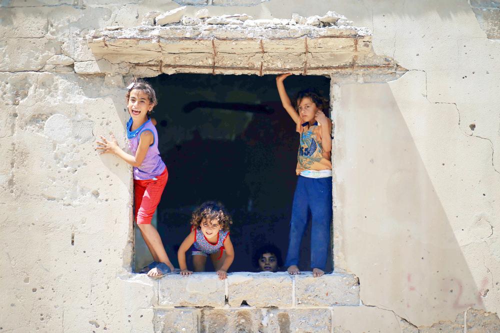 



أطفال فلسطينيون يلعبون في نافذة منزل داخل معسكر للاجئين في غزة أمس. (أ. ف. ب)