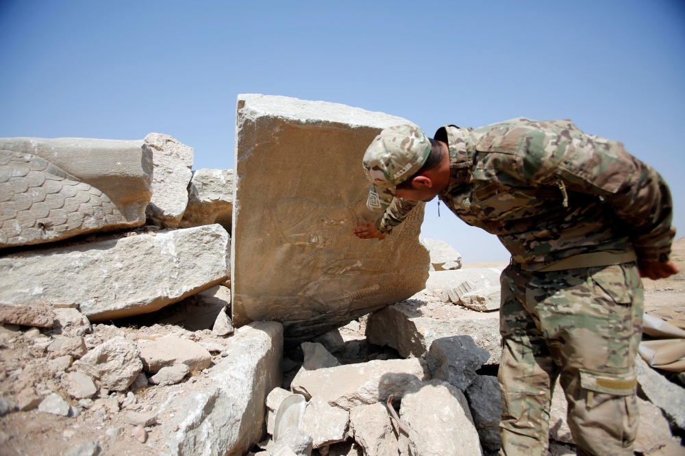 جندي عراقي يطالع بقايا ألواح الجدران والتماثيل الضخمة للثيران المجنحة التي دمرها 
