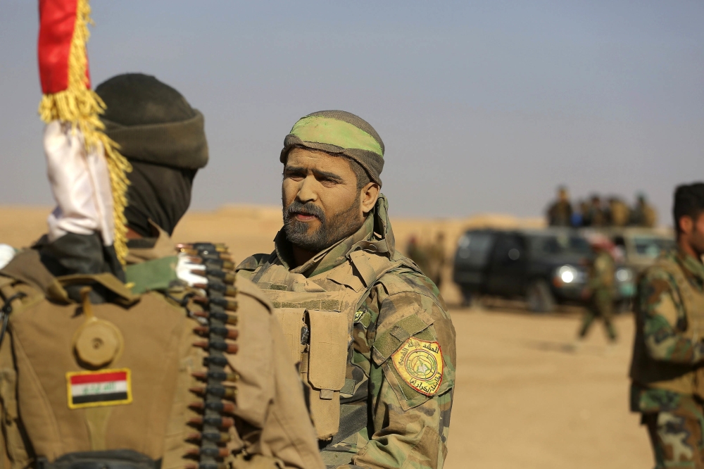 FILE - in this Saturday, Nov. 26, 2016 file photo, fighters of the Popular Mobilization Forces stand at the front line against Islamic State Group militants outside Mosul, Iraq. Iraq's mostly Shiite militia forces say they will participate in the next major battle against IS in Iraq after victory was declared in Mosul last month. (AP Photo/Anmar Khalil, File)