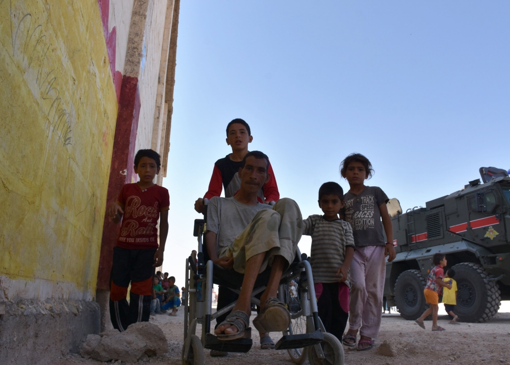 Displaced Syrian families who are staying at a temporary shelter in Jibrin, on outskirts of Aleppo, are seen before they are transported to areas currently controlled by the Syrian regime in eastern Aleppo on August 16, 2017. / AFP / George OURFALIAN
