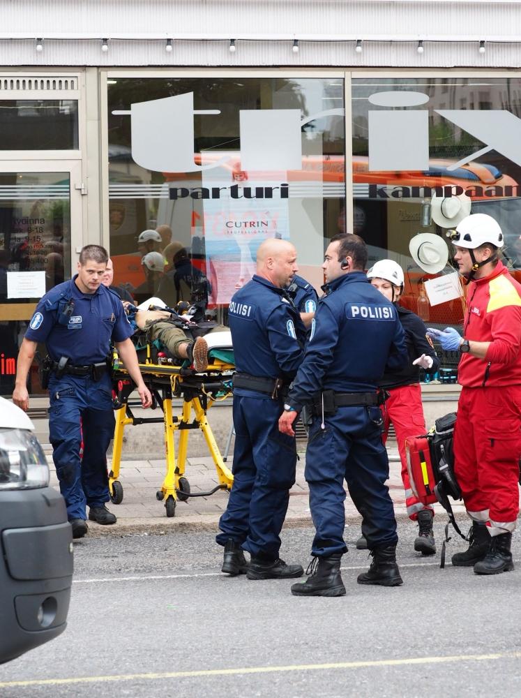 يقف ضباط الشرطة ورجال الإنقاذ بجانب شخص مصاب فى الهجوم الذي وقع في مدينة توركو اليوم الجمعة. (أ ف ب)