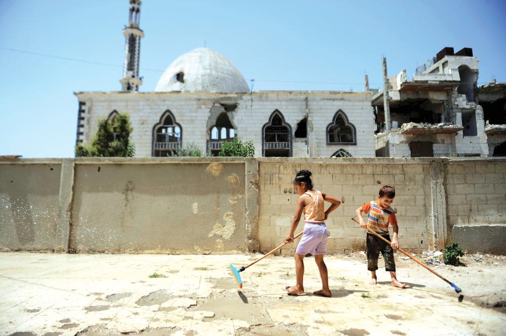 



طفلان سوريان ينظفان ساحة أمام مسجد في حي بابا عمرو في حمص. (رويترز) 