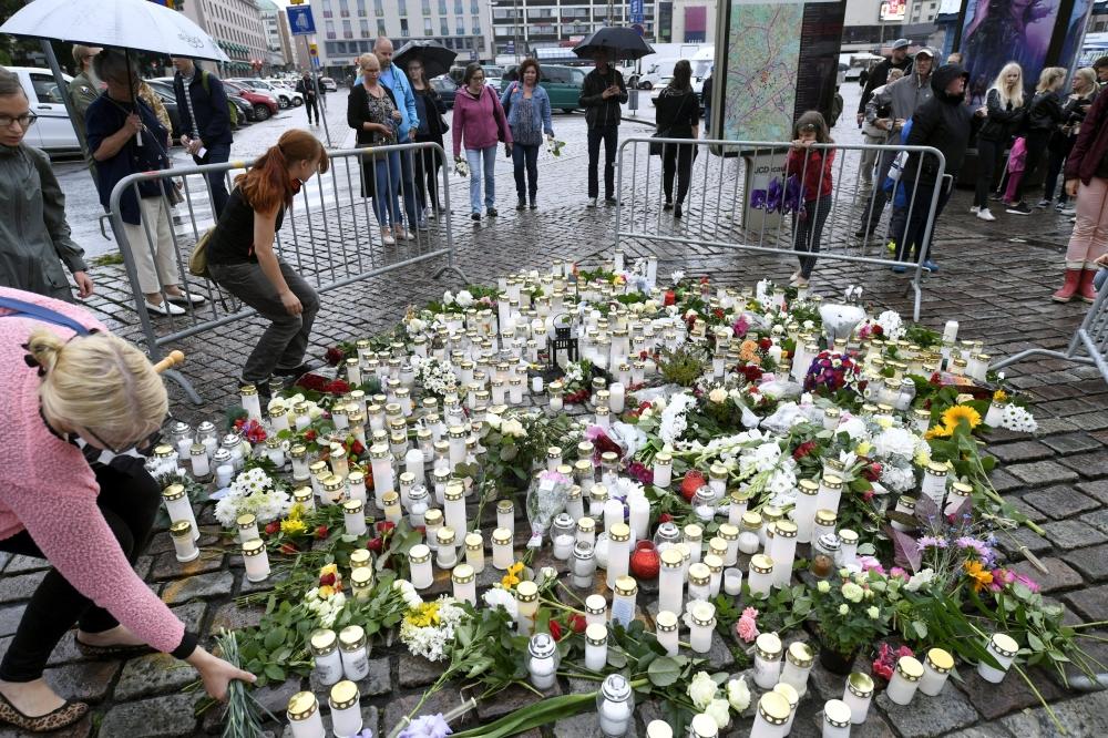  مواطنون فنلنديون يضعون الشموع والزهور على النصب التذكاري لضحايا حادث الطعن الذي وقع أمس الجمعة بتوركو. (رويترز)