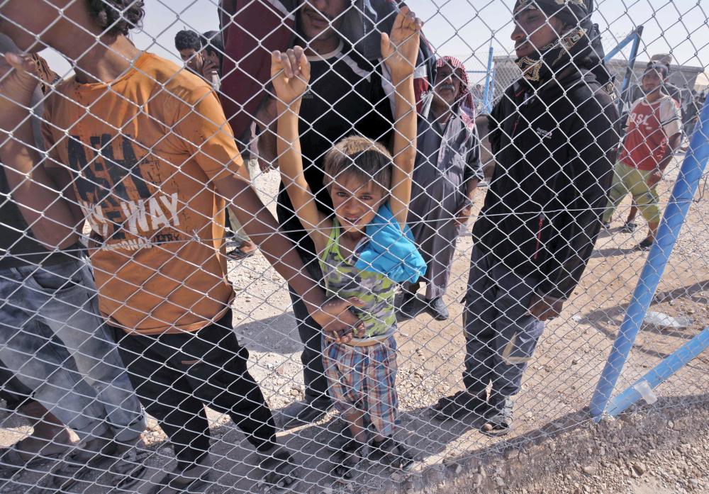 نازحون سوريون ينتظرون تلقي الطعام في مخيم بقرية رأس العين على الحدود السورية التركية أمس الأول.( ا ف ب)