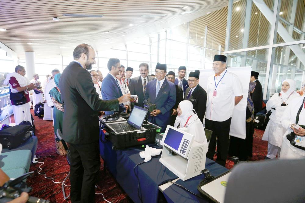 



مسؤولو الجوازات السعودية في مطار كوالالمبور خلال تسجيل البصمات الحيوية للحجاج الماليزيين.  (عكاظ)