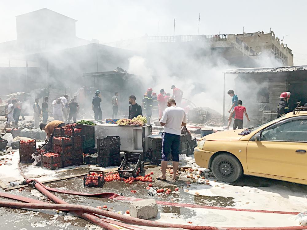  رجال الإطفاء يخمدون حريقا في موقع انفجار سيارة ملغومة في سوق بمدينة الصدر أمس. (أ ف ب)