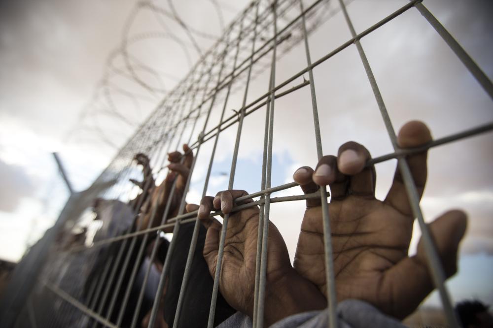 TOPSHOTS
African asylum seekers, who entered Israel illegally via Egypt, lean at the fence of the Holot detention centre in Israel's southern Negev Desert, on February 17, 2014 as they join other migrants who came to protest outside the detention facility.  The Israeli government has opened last year the sprawling Holot detention facility to house both new entrants and immigrants already in the country deemed to have disturbed public order. Tens of thousands of migrants, mostly Eritrean and Sudanese, have been staging mass demonstrations in the country against moves by the Israeli authorities to track them down and deport them, or throw them into detention facilities without trial.  AFP PHOTO/JACK GUEZ