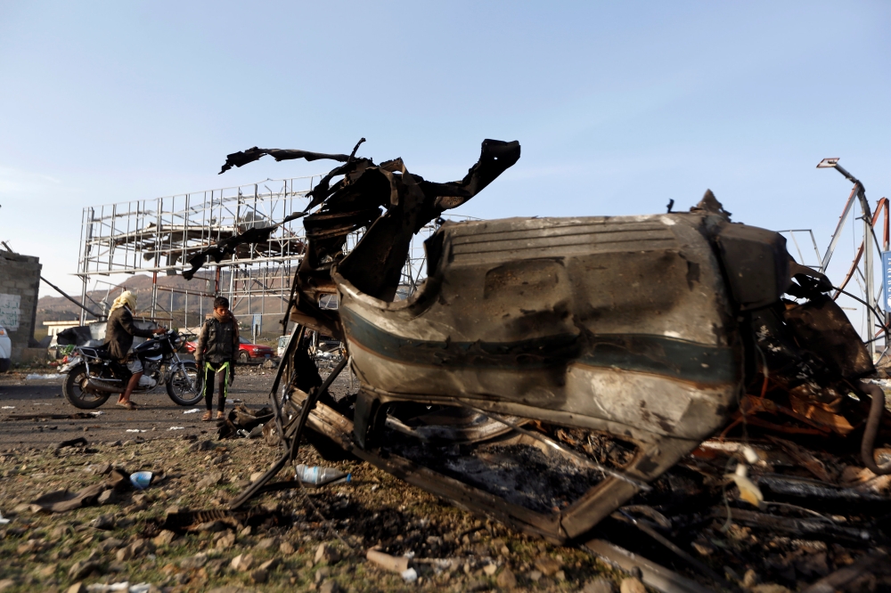 A boy looks at the wreckage of a taxi car destroyed by a Saudi-led air strike on a checkpoint of the armed Houthi movement near Sanaa, Yemen August 30, 2017. REUTERS/Khaled Abdullah