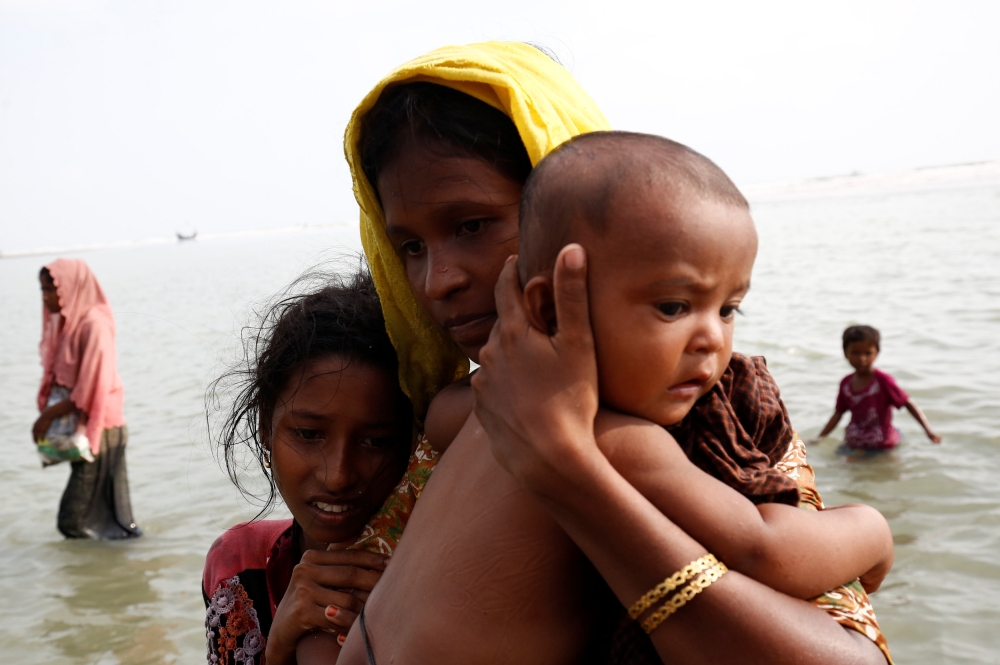 Rohingya refugee woman and children walks to the shore after crossing the Bangladesh-Myanmar border by boat through the Bay of Bengal in Teknaf, Bangladesh, September 5, 2017. REUTERS/Mohammad Ponir Hossain