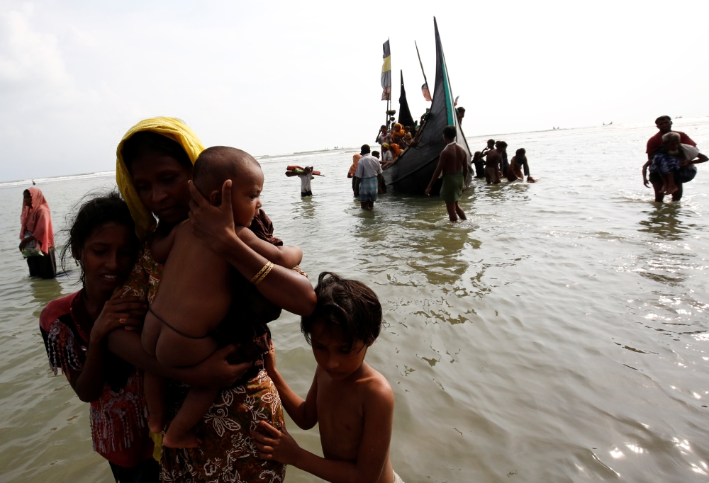 Rohingya refugee woman and children walks to the shore after crossing the Bangladesh-Myanmar border by boat through the Bay of Bengal in Teknaf, Bangladesh, September 5, 2017. REUTERS/Mohammad Ponir Hossain