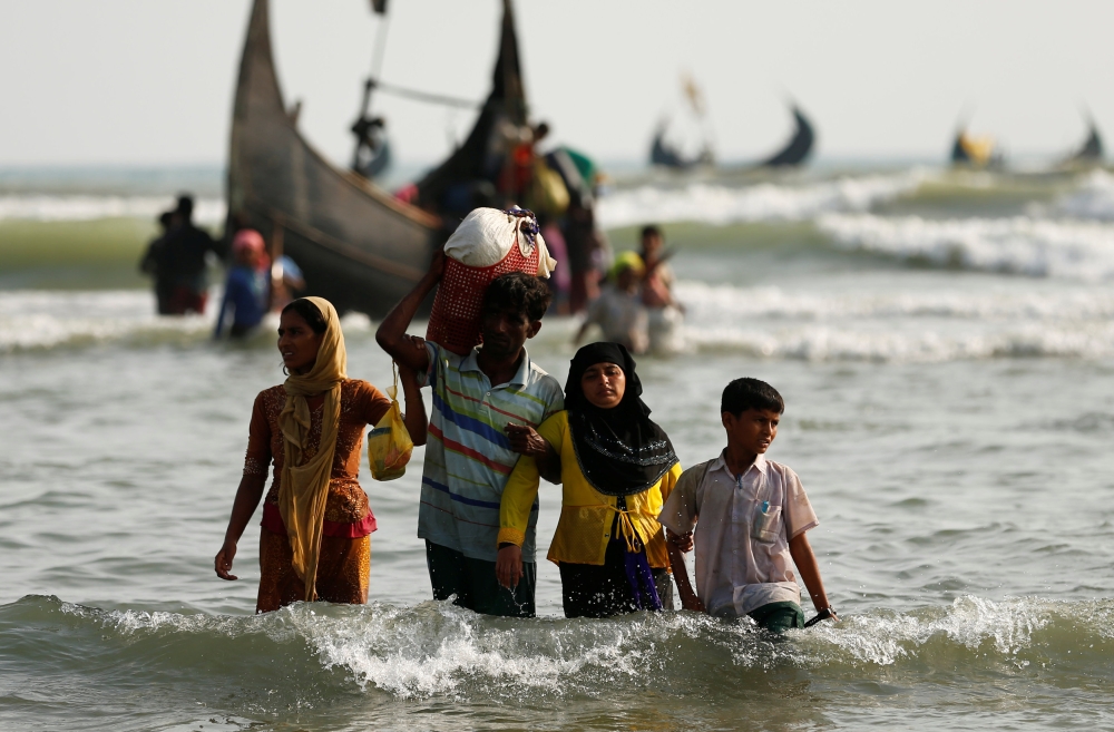 Rohingya refugees walk to the shore with his belongings after crossing the Bangladesh-Myanmar border by boat through the Bay of Bengal in Teknaf, Bangladesh, September 5, 2017. REUTERS/Mohammad Ponir Hossain
